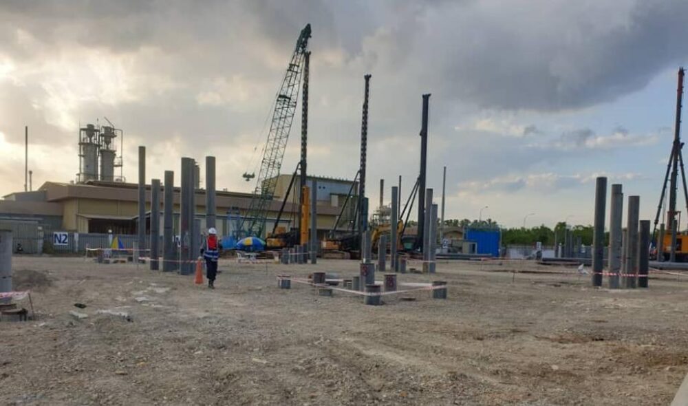 Piling rig driving concrete piles at an industrial site